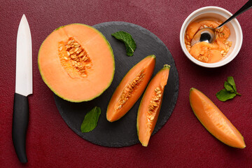 Slate board with tasty ripe melon on red background