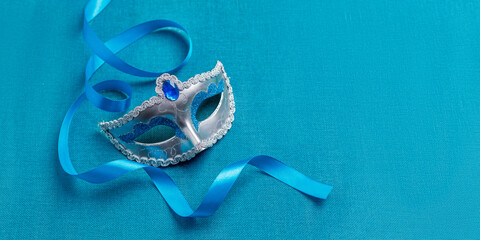 Carnival masks with a blue ribbon, on a turquoise background. Purim holiday , Mardi Gras. Banner