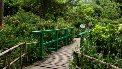 Obraz premium Bridge through plants and flowers in Monet's Garden on a summer day in Giverny, France.