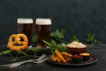 Glasses of cold beer with Bavarian sausages, sauces and sauerkraut on dark grunge background. Oktoberfest celebration