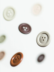 Colorful buttons falling on white background: sewing and fashion concept