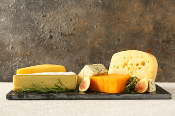 Board with tasty cheese on table near brown wall