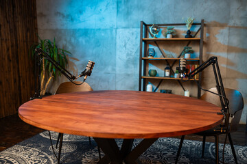 Podcast recording setup featuring microphones and a wooden table in a modern studio environment