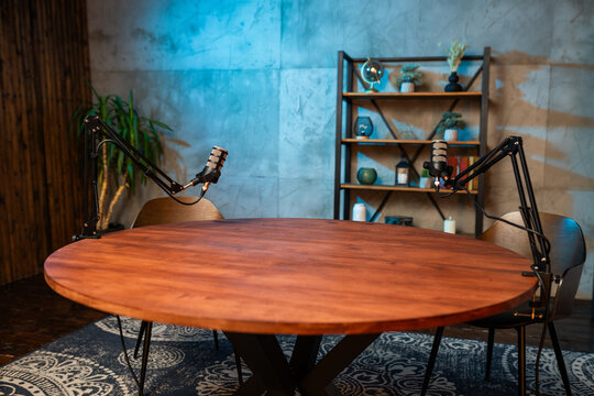 Podcast recording setup featuring microphones and a wooden table in a modern studio environment