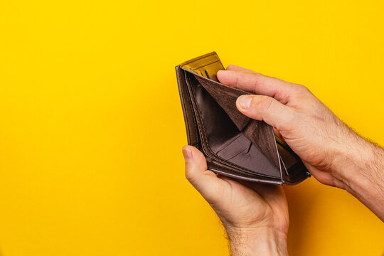 Hands holding an empty wallet on a bright yellow background