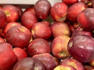 Box filled with fresh natural bio organic red coloured apples placed on counter in local food market. Close-up