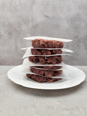 Raw beef burger patties stacked on baking paper in prague