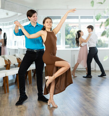 Couples in evening dresses suits enjoys pair dance tango, positively interacting with each other on...