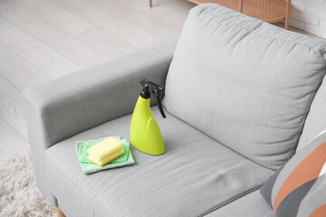 Bottle of mold remover, sponge and rags on sofa