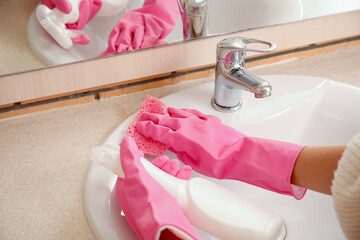 Woman with rag removing mold from sink in bathroom, closeup