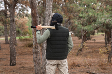 Fototapeta premium Male lumberjack with axe in forest, back view
