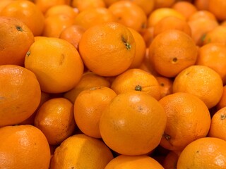 A box of ripe, fresh yellow oranges is for sale on the shelf of a fruit supermarket. Close-up
