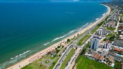 Fototapeta premium Linda vista aerea com drone sobre o mar com montanhas e cidade ao fundo com cores vibrantes.