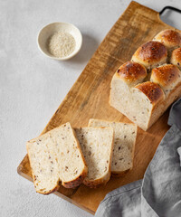 Freshly baked whole grain bread with slices on a wooden board with a sesame seeds and napkin