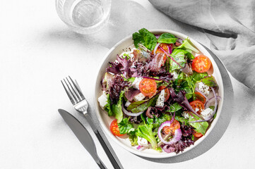 Vegetable salad (Greek salad) with cherry tomatoes, feta cheese, lettuce, olives and red onion in a plate
