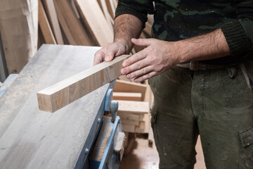A carpenter inspects a molded piece of ash wood