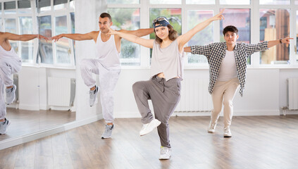Naklejka premium Active young men and girls practicing hip-hop dance in training hall during group dancing classes