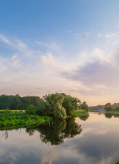 Calm river with a few trees in the background