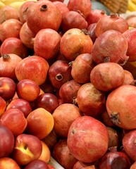 Lots of ripe red pomegranates on a market counter for sale on sale in vegetable stand display at supermarket show organic food, vegetarian food, healthy food. Close-up