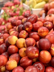 A lot of fresh red yellow colored peaches on market stall or in groceries shop area. Nectarines background. Fruit food background. Close-up