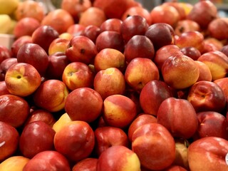 A lot of fresh red yellow colored peaches on market stall or in groceries shop area. Nectarines background. Fruit food background. Close-up