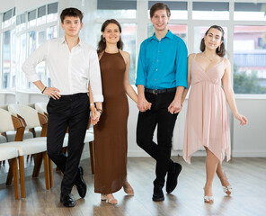 Group of young men and women dancing folk dance in row in studio