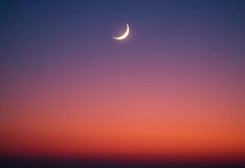 A crescent moon with a sprinkling of stars in the reddening sky