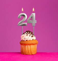 Birthday candle number 24 with cupcake on violet background.