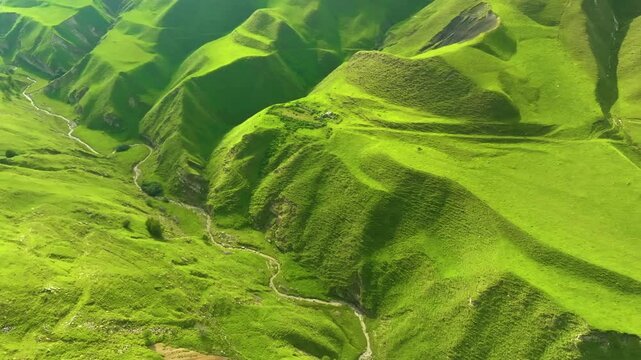 Aerial drone footage of Maltas Canyon, Dagestan, highlighting rugged terrain, dense greenery, a winding mountain river, and shifting cloud shadows over peaks.