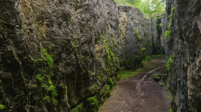 Aerial drone footage of Maltas Canyon, Dagestan, showcasing moss-covered mountains and a wide valley between towering peaks.