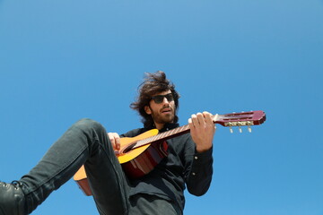 Young Long Hair Man Plays Classical Guitar Outside, Low Angle
