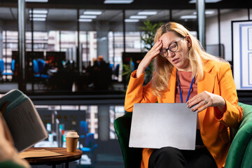 Unwell overworked businesswoman dealing with a headache during briefing meeting, working under...