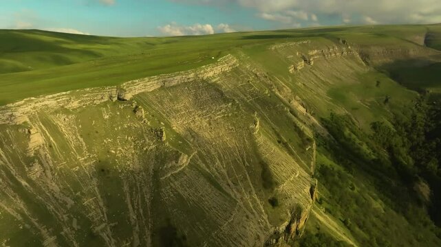Aerial shot of the Barmamit Plateau, Kabardino-Balkaria, capturing rolling green landscapes, alpine forests, and misty clouds in summer weather.