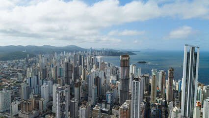 Drone perspective of Balneário Camboriú, showing the vibrant city with tall, modern skyscrapers along the coast and the endless Atlantic Ocean in the distance.