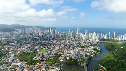 High-altitude drone photo of Balneário Camboriú, Brazil, capturing the cityscape, the BR-101 highway, and the vast Atlantic Ocean in the background.