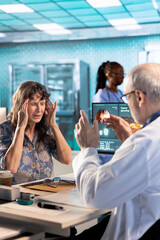 Fototapeta premium Old woman patient suffers from a painful migraine and asks for advice at checkup with medic, general practitioner recommending a treatment to relieve pain and ease the inflammation. Health insurance.