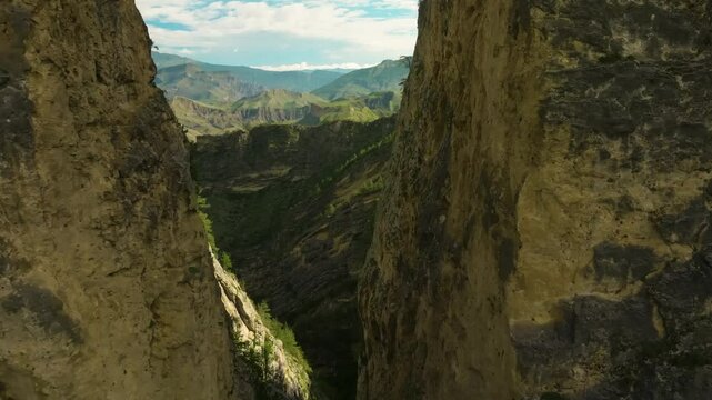 Drone footage of Karadakh Gorge, Dagestan, navigating closely between two towering mountains covered in alpine forests.