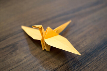 Delicate Pale Yellow Origami Crane Artistically Positioned on Dark Wooden Surface
