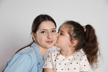 Cute little girl kissing her sister on white background