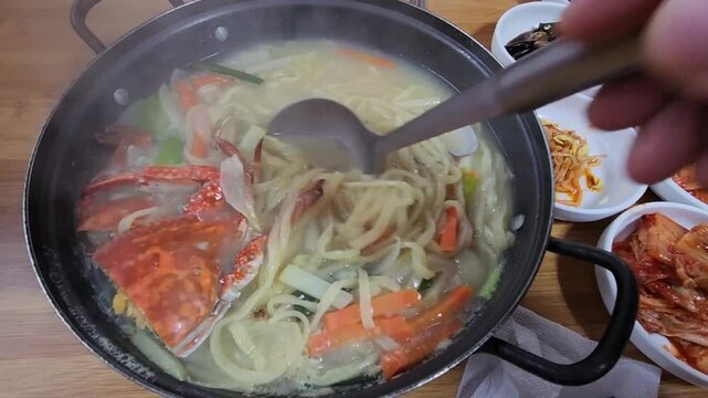 한국 충청남도 태안군 몽산포의 꽃게 칼국수가 하얀김이 나면서 뜨겁게 조리되어 국자로 떠내는 