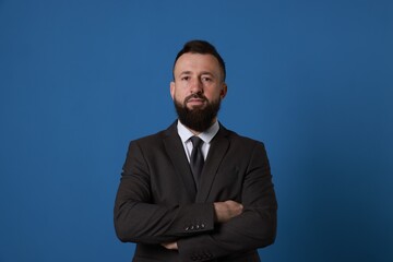 Handsome bearded man in suit on blue background