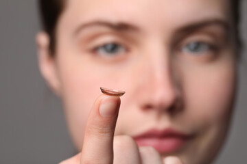 Woman with color contact lens on grey background, closeup. Selective focus