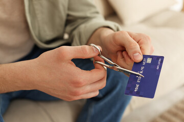 Man cutting his credit card indoors, closeup