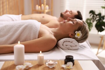 Couple lying on massage tables in spa salon, selective focus