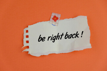 a torn notepad with text of BE RIGHT BACK on orange  background as a memo or message concept. 