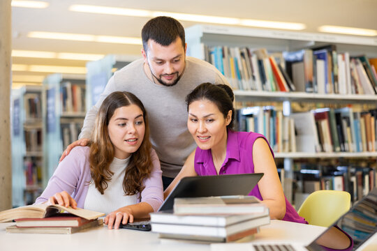 Friendly group of students is preparing for classes on a laptop, studying in the university library