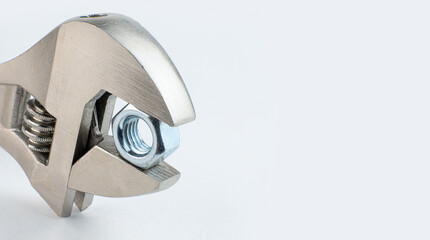Adjustable wrench holding a metal nut. copy space