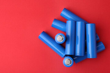 Many AA cell batteries on red background, top view. Space for text