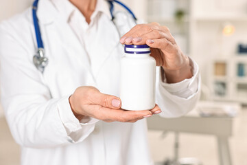 Nutritionist with bottle of weight loss pills in clinic, closeup