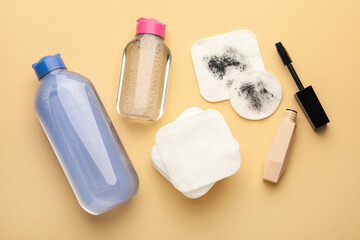Clean and dirty cotton pads, mascara, micellar water on beige background, flat lay
